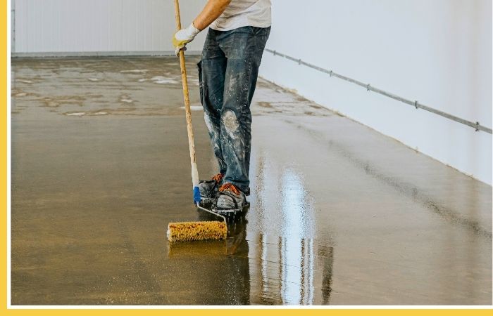 A worker sealing a concrete floor