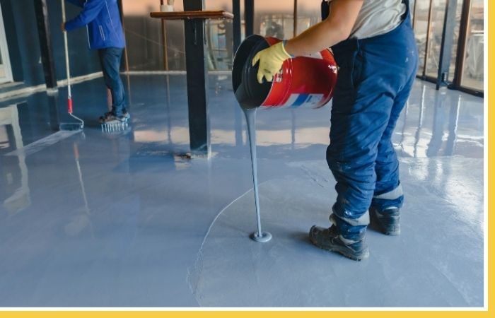 A worker applying concrete floor coating