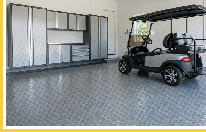 A clean, organized garage in a lakeside home with a new grey polyurea floor, storage cabinets, and a golf cart.