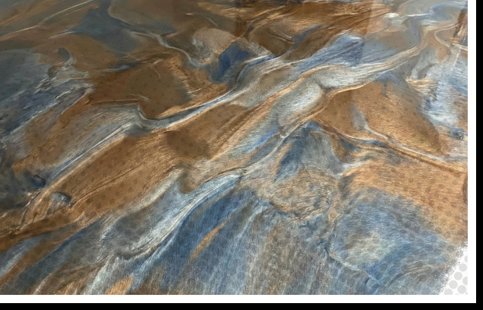 A close-up of a custom metallic concrete floor with swirls of bronze, silver, and blue tones.
