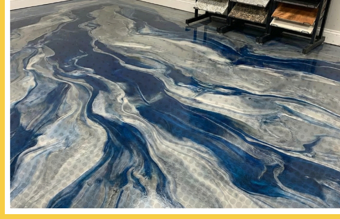 Custom metallic concrete floor with a blue and silver marbled design, next to a display rack of flooring samples.